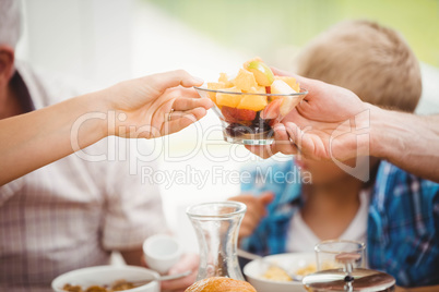 Close-up of hands passing bowl of fruits