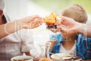 Close-up of hands passing bowl of fruits