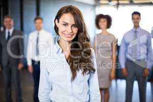 Businesswoman smiling at camera while his colleagues standing in