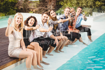 Young people sitting by swimming pool