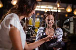 Smiling woman paying with smartphone