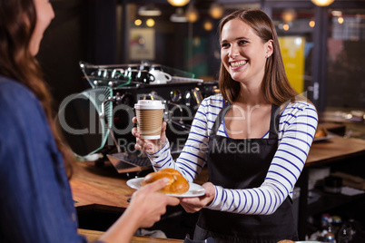 Pretty barista holding disposable cup and brioche