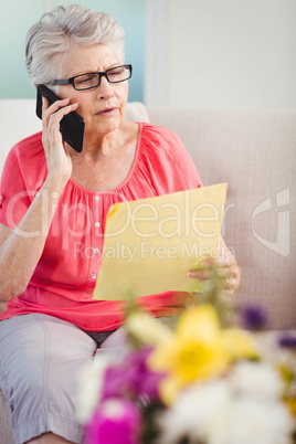 Senior woman reading a letter and talking on phone Senior woman reading a letter and talking on phone