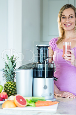 Blonde woman holding a smoothie glass in the kitchen