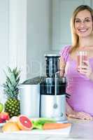 Blonde woman holding a smoothie glass in the kitchen