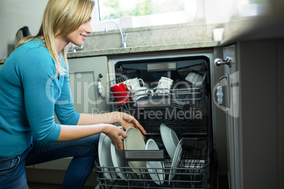 Pretty blonde woman emptying the dishwasher