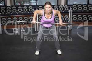 Determined woman lifting barbell