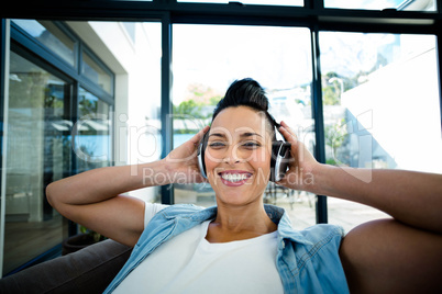 Portrait of pregnant woman listening to music on sofa