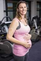 Smiling pregnant woman touching her belly