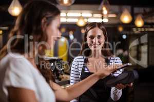Smiling woman paying with smartphone