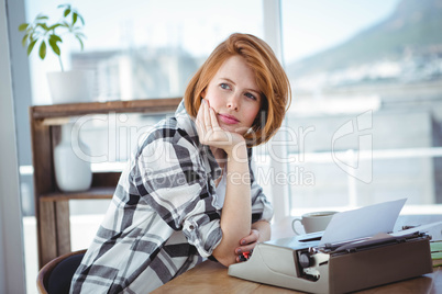 hipster woman sitting at her typewriter, thinking