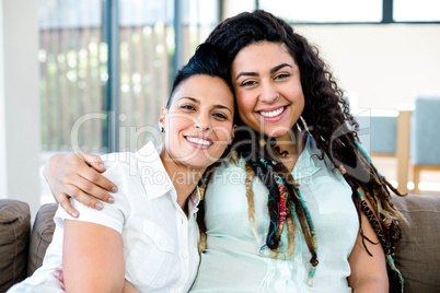 Smiling lesbian couple embracing and relaxing on sofa