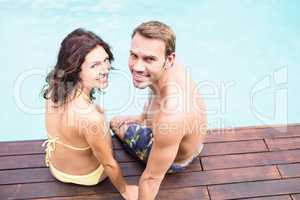 Young couple sitting by poolside