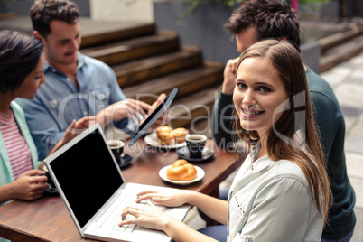 Smiling woman using laptop at the bar