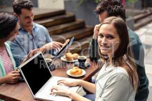Smiling woman using laptop at the bar