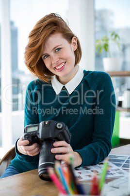 smiling hipster photographer looking at pictures on her camera