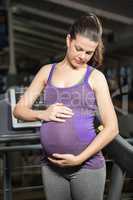 Standing pregnant woman touching belly