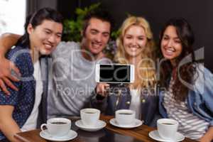 Smiling friends enjoying coffee and taking selfie