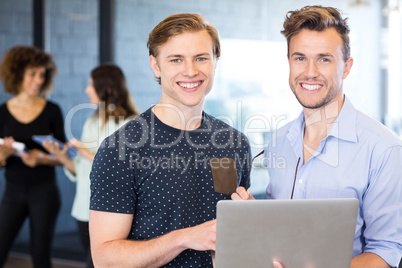 Portrait of men holding a laptop and smiling