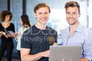 Portrait of men holding a laptop and smiling