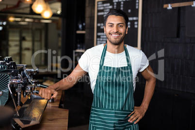 Smiling barista standing next coffee machine