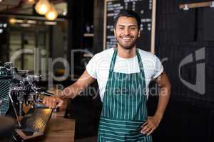 Smiling barista standing next coffee machine