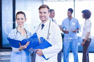 Doctors with medical report looking at camera and smiling