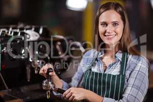 Smiling barista preparing coffee with machine