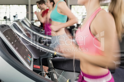 Fit woman running on the treadmill while listening music