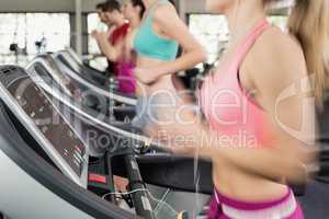 Fit woman running on the treadmill while listening music