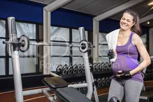 Smiling pregnant woman standing next to bench