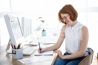 smiling hipster businesswoman sketching at her desk