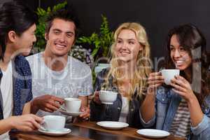 Smiling friends talking and enjoying coffee