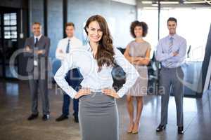 Businesswoman smiling at camera while her colleagues standing in