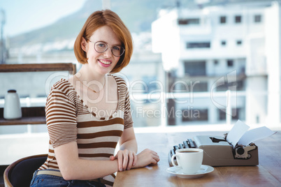 smiling hipster woman with coffee and a typewriter