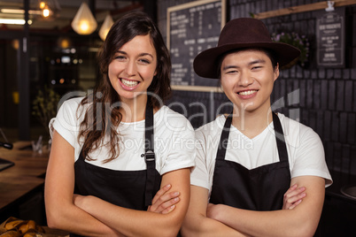 Smiling co-workers posing with crossed arms