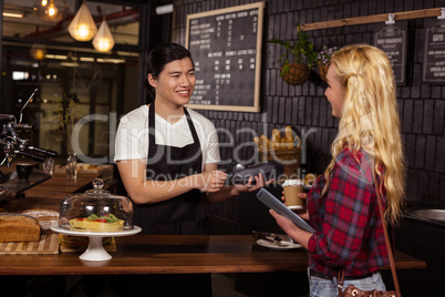 Smiling barista taking credit card from customer