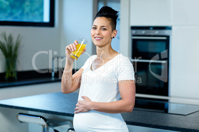 Portrait of pregnant woman drinking juice in kitchen