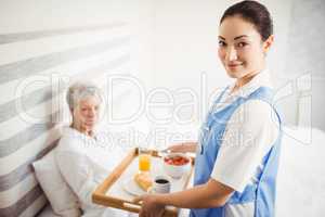 Nurse giving breakfast to senior woman