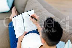 Pregnant woman writing on notepad