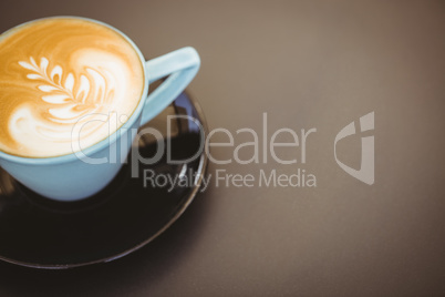 Cup of cappuccino with coffee art on wooden table