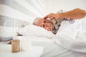 Frustrated senior man lying in bed
