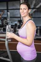 Smiling pregnant woman holding bottle of water