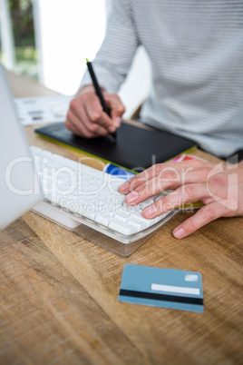 Masculine hands taking notes and typing on keyboard