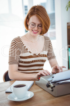 smiling hipster woman with coffee and a typewriter