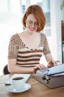 smiling hipster woman with coffee and a typewriter