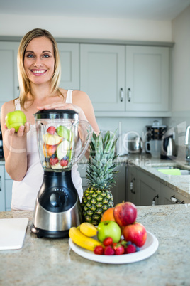 Pretty blonde woman preparing a smoothie