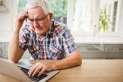 Worried senior man using laptop