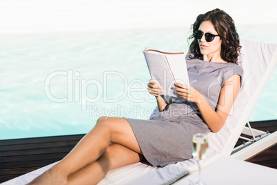 Young woman reading magazine near poolside