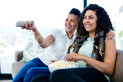 Lesbian couple watching television with a bowl of popcorn
